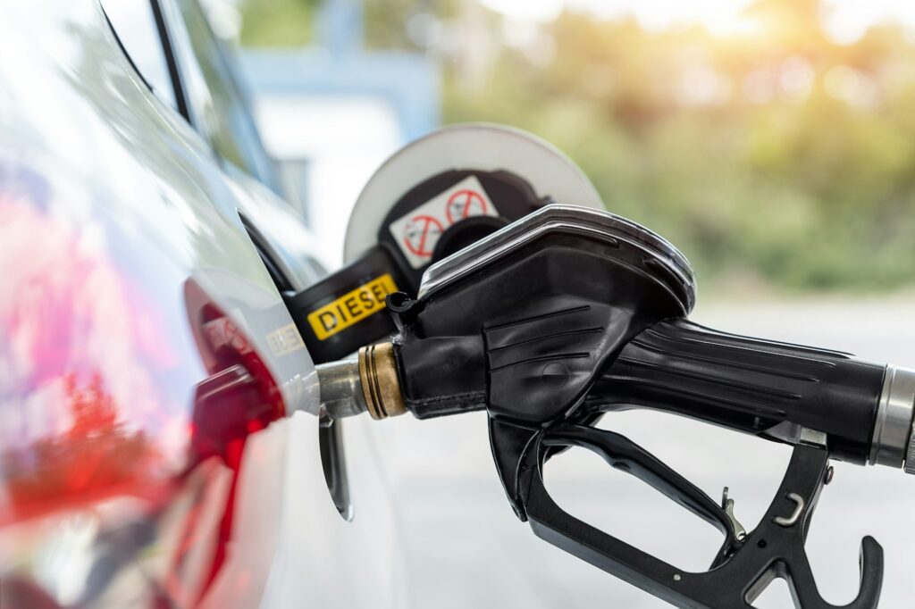 Close-up detail view of black pistol handle inserted in white diesel car fuel tank refueling at