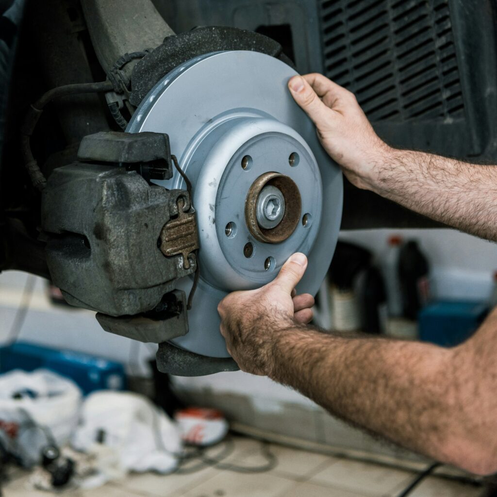 cropped view of auto mechanic holding metallic car brake near auto