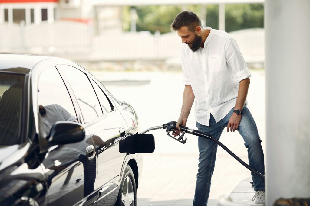 Handsome man pours gasoline into tank of car